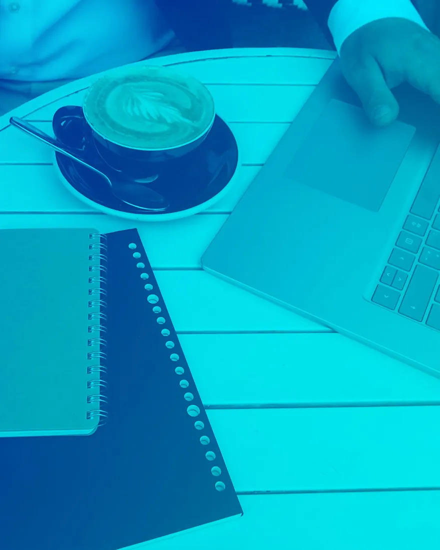 Blaue Duotone: Notizbuch, Kaffee und Laptop auf einem Arbeitstisch
